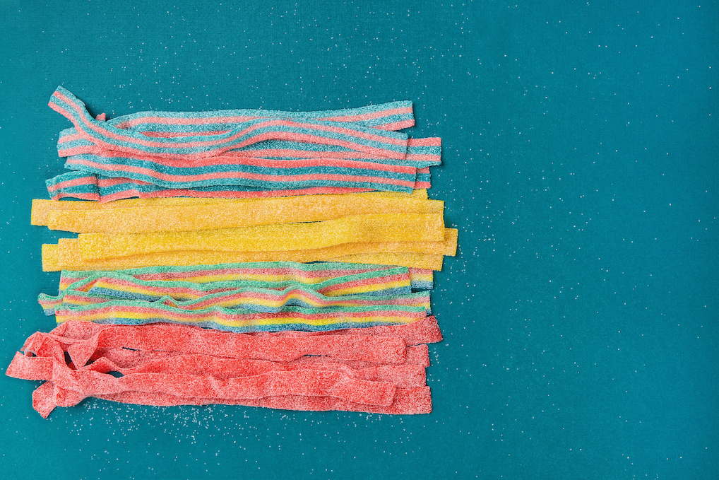 Rows of different flavored sour belts on a blue background