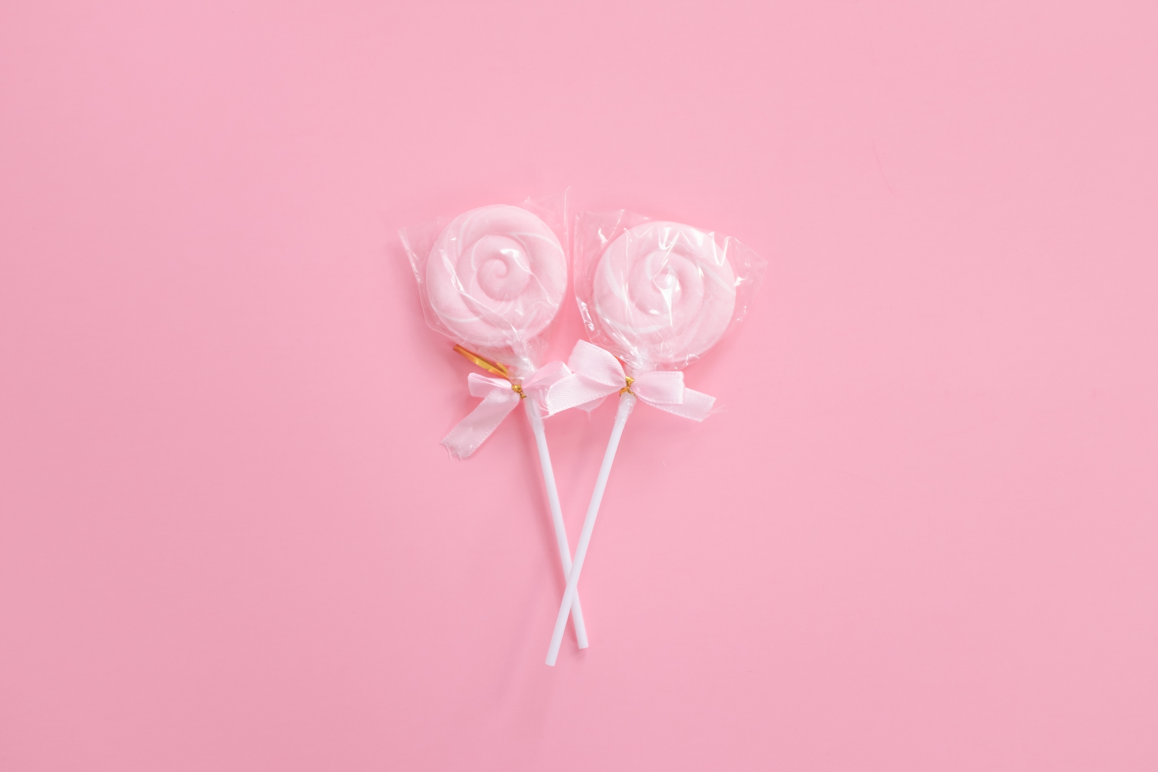 Two pink swirl lollipops on a pink background